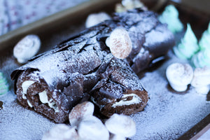 Yule log cake. Chocolate cake rolled with whipped cream decorated with mushrooms and trees.