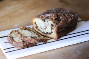 loaf of cinnamon bread sitting on a cutting board with two slices cut off the end